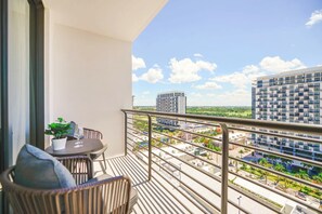 A balcony with a table, chairs, and a potted plant. - Prime Downtown Doral Park Condo (Doral)