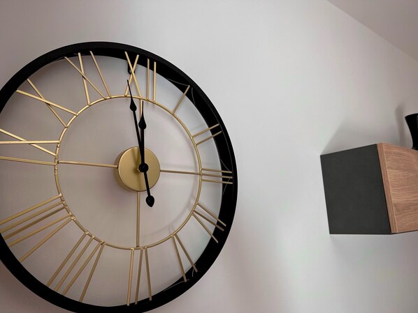En stor väggklocka med en minimalistisk design, med en rund urtavla och romerska siffror.