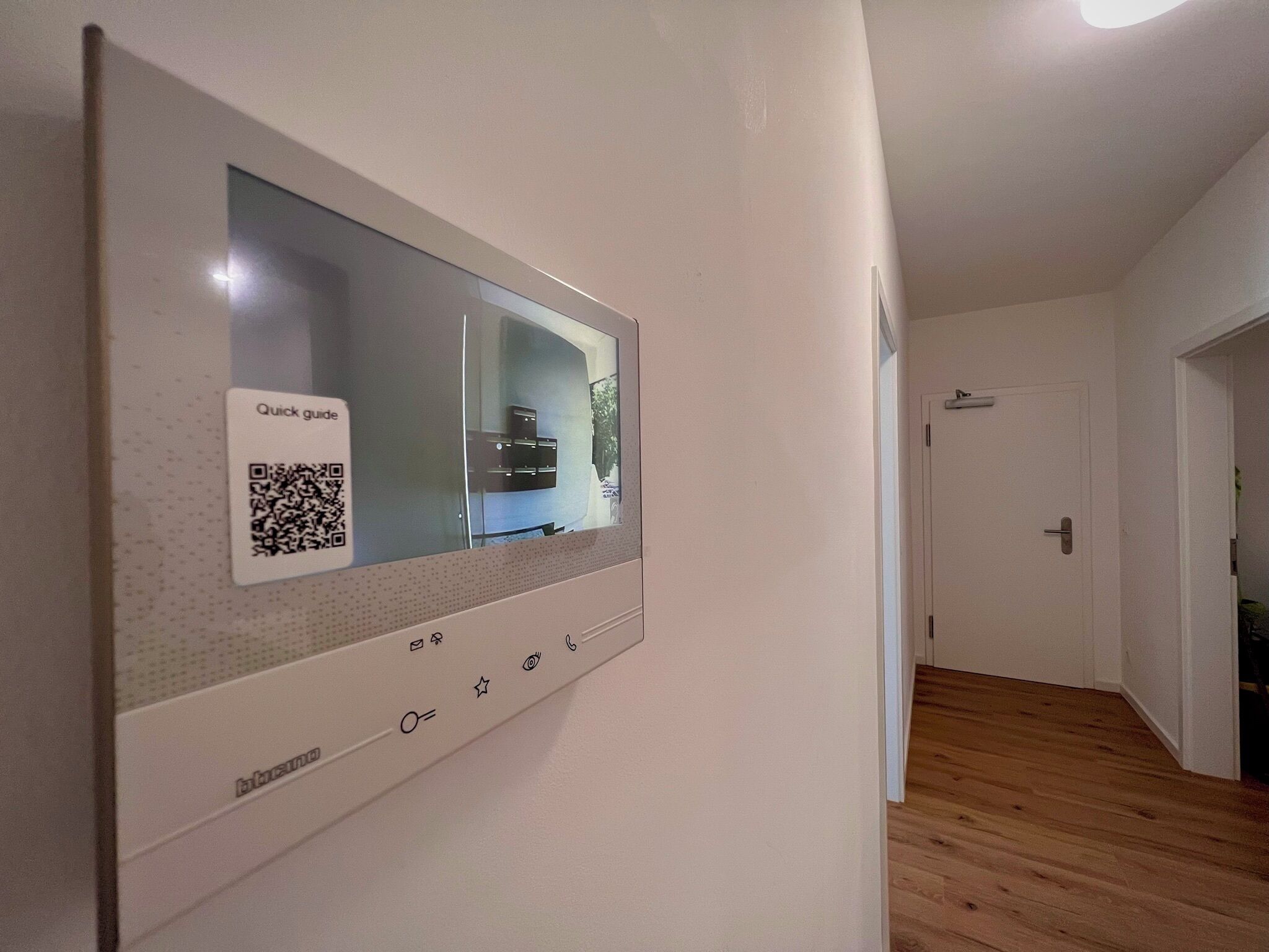 A wall-mounted control panel with a QR code and a display screen.