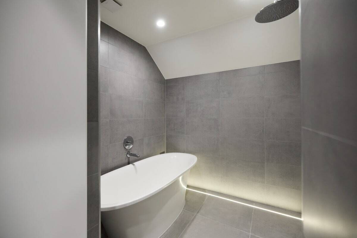 Une salle de bain moderne avec une baignoire sur pieds, des spots encastrés au plafond et un espace douche.