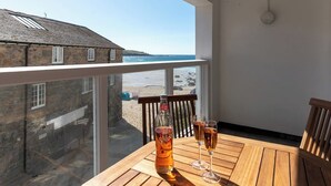 A wooden table with a bottle and glasses on a balcony overlooking a beach. - 3 St Nicholas Court - St Ives (St Ives)