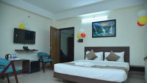 A hotel room with a bed, a desk, a chair, a television, and a painting on the wall. - Hotel Crown Castle (Guwahati)