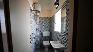 A compact bathroom with a toilet, sink, and a mirror. The walls are tiled with a checkered pattern. - Hotel Crown Castle (Guwahati)