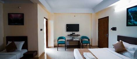 A hotel room with a bed, a desk with two chairs, a television, and a door.