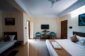 A hotel room with a bed, a desk with two chairs, a television, and a door. - Hotel Crown Castle (Guwahati)