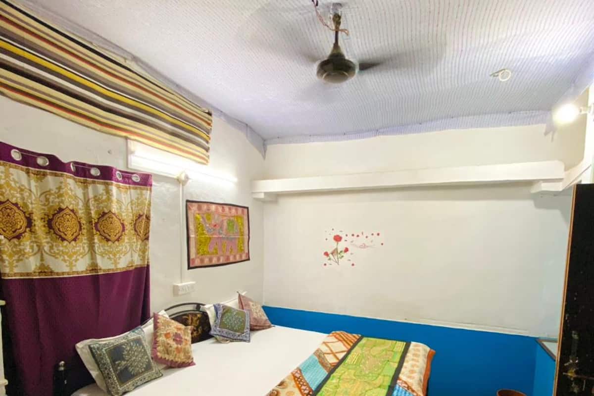 Ein Schlafzimmer mit einem Bett, Vorhängen, einem Deckenventilator, einer Wanddekoration und einem gemusterten Boden.