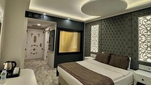 A modern hotel room with a large bed, a desk, and a red chair. - Golden Rose Deluxe Hotel (Manisa)