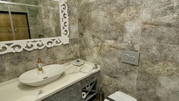 A bathroom with a marble sink, vanity, and toilet.
