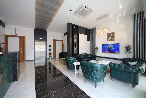 A modern lobby with a reception desk, seating area, and a TV. - Golden Rose Deluxe Hotel (Manisa)