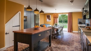 A kitchen with a herringbone floor, a central island, pendant lighting, and a view of the outdoors. - Otmoor House - Beckley, Near Oxford (Beckley)