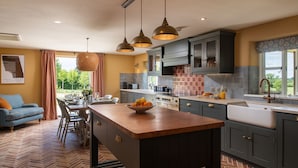 A modern kitchen with dark cabinetry, a central island, and pendant lighting. - Otmoor House - Beckley, Near Oxford (Beckley)