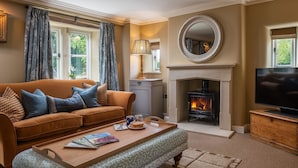 A living room with a sofa, coffee table, fireplace, television, and a mirror on the wall. - Otmoor House - Beckley, Near Oxford (Beckley)