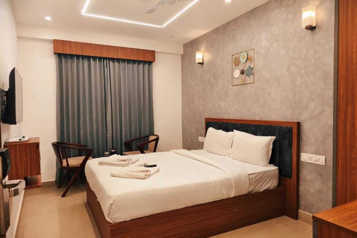 A hotel room with a bed, a desk, a chair, a TV, and a ceiling fan.