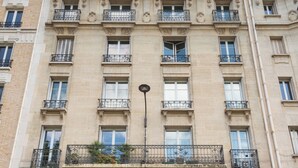 A multi-story building with a classic architectural style, featuring ornate balconies, large windows, and a prominent entrance with a black door. - Opulent 1BD Apartment near Eiffel Tower, Grenelle (Paris)