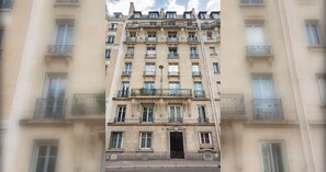 A multi-story building with a symmetrical facade, featuring evenly spaced windows and balconies with wrought iron railings.