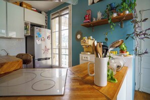 Een keuken met een houten aanrecht, een witte mok en een raam met jaloezieën.