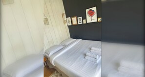 Een slaapkamer met een bed, kussens en een wandplank met ingelijste foto's.