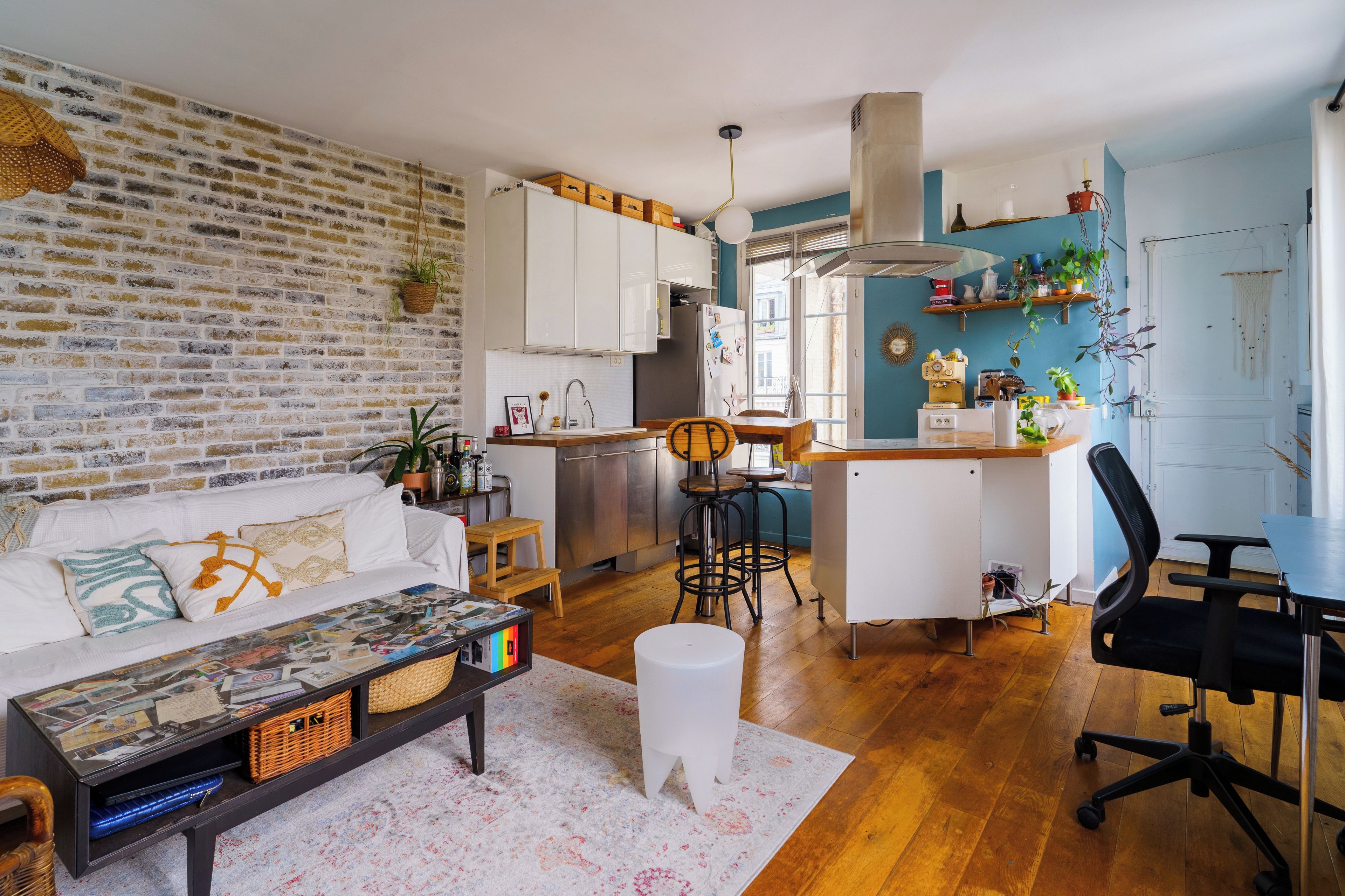 Um espaço de estar compacto com cozinha, área de refeições e sala de estar com sofá e mesinha de centro.