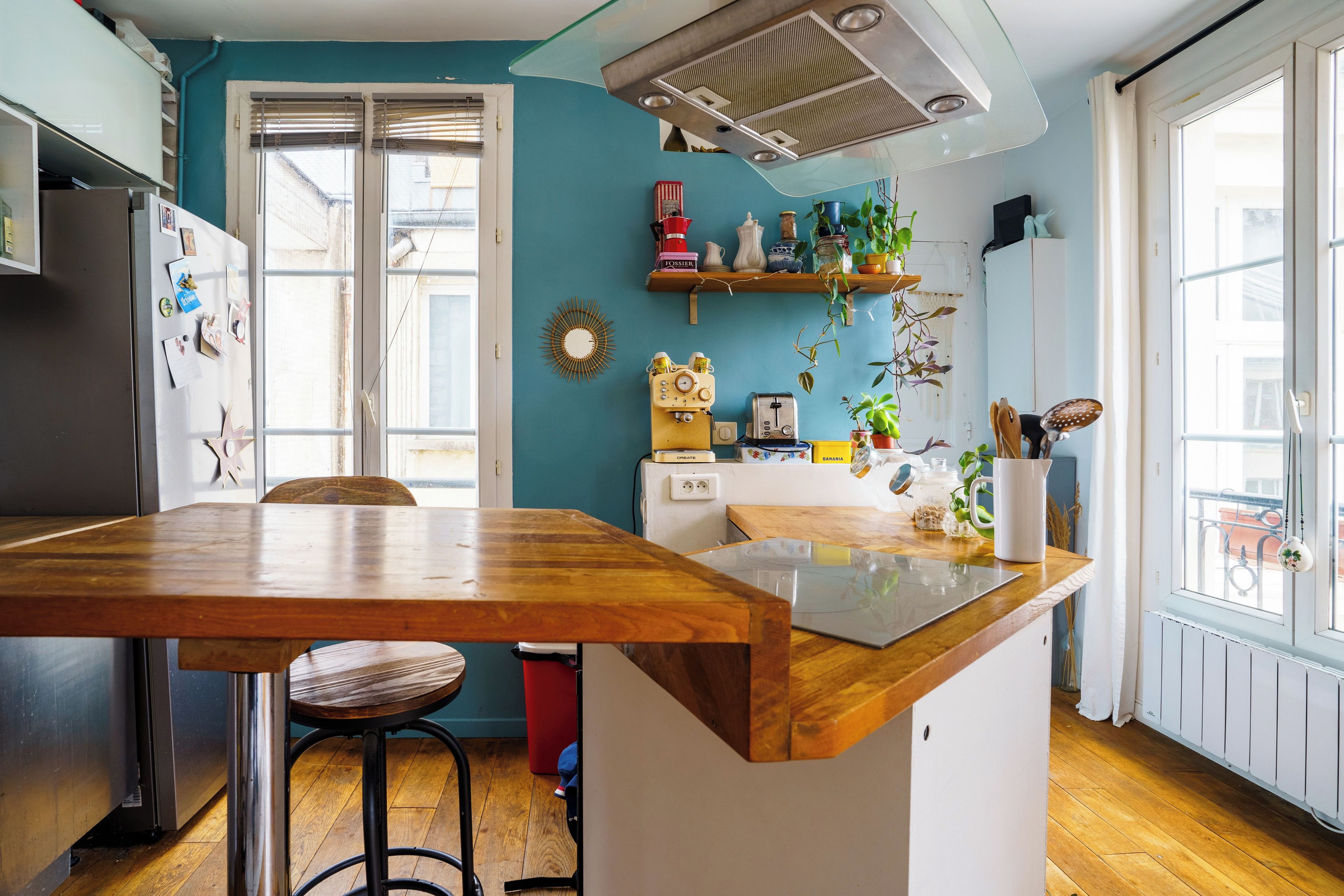 A kitchen with a wooden island, a refrigerator, a sink, and a window with a view.