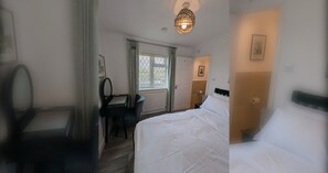 A hotel room with a bed, a desk with a chair, a mirror, a window with curtains, and a door. - Thames Riverside Retreat: A Serene 3-Bed Bungalow (Surrey)