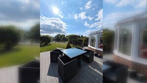 A patio with a glass-top table and chairs, surrounded by a wooden deck.