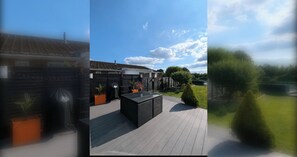 A patio area with a built-in barbecue grill, a seating area, and a view of a residential property.