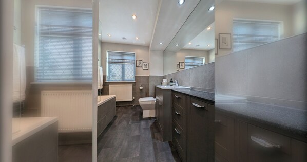 A modern bathroom with a toilet, sink, and shower area. - Thames Riverside Retreat: A Serene 3-Bed Bungalow (Surrey)