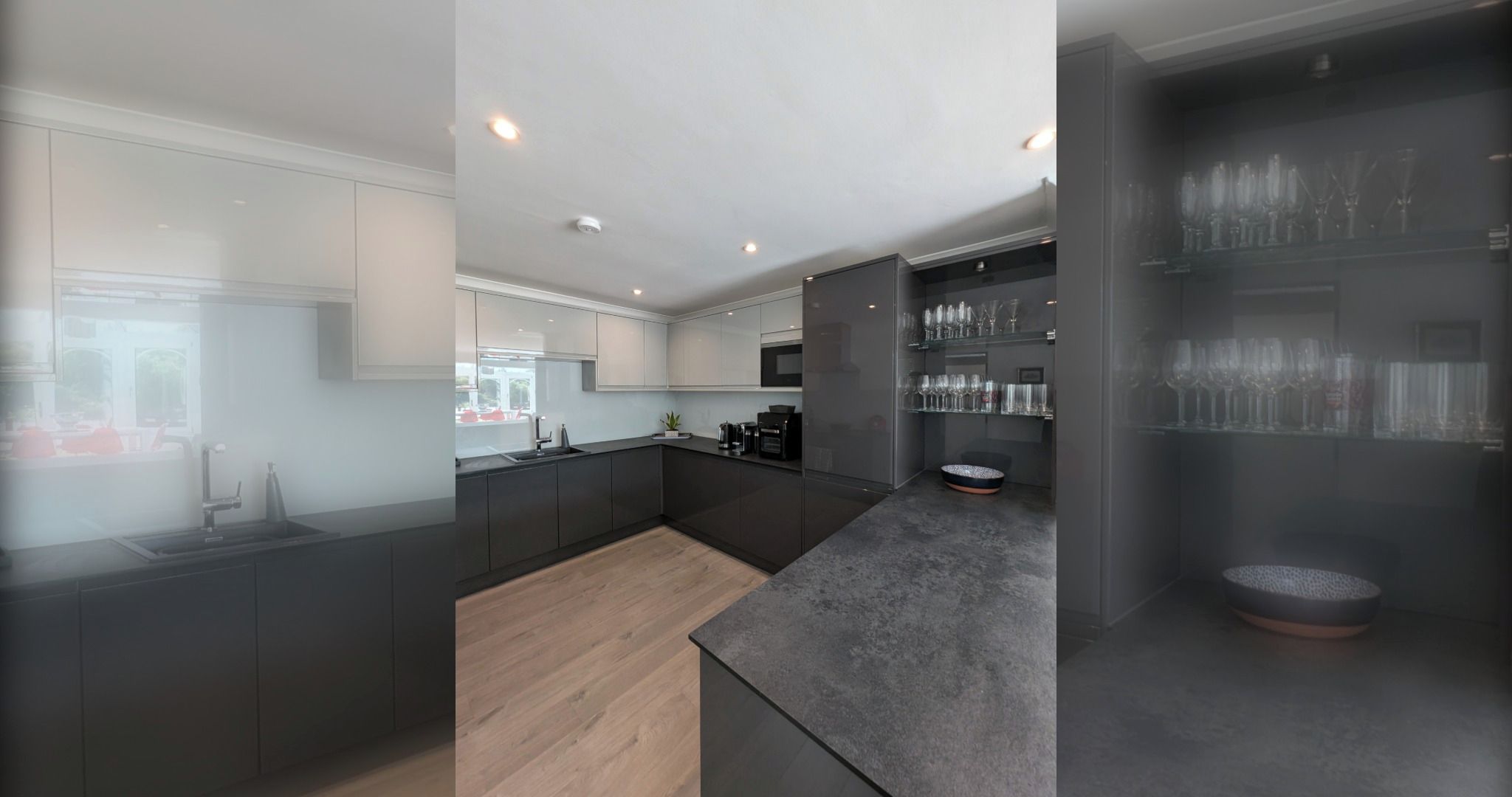 Una cocina moderna con una isla central, un comedor con mesa de vidrio y una zona de bar con vitrina de cristal.