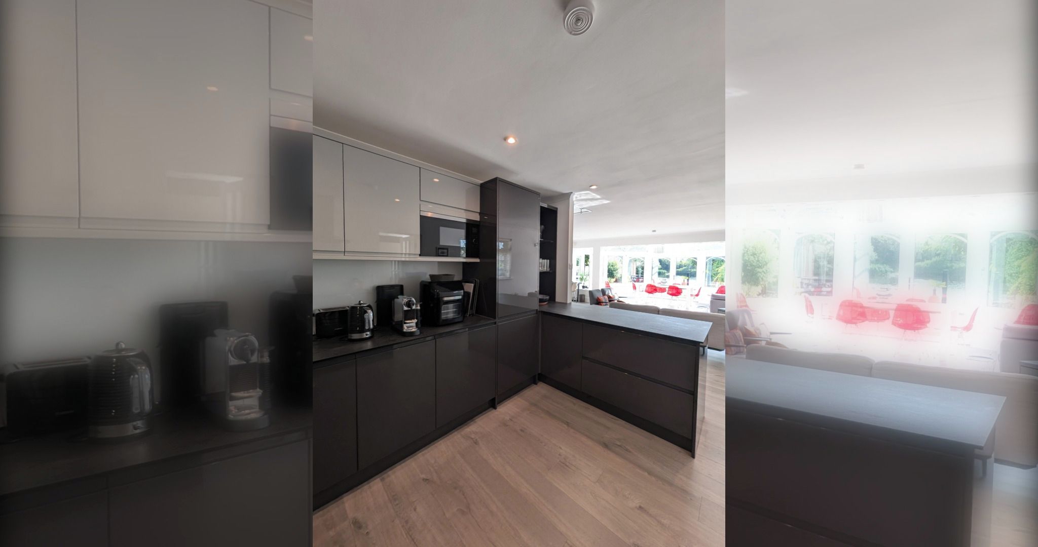 A modern kitchen with dark cabinetry, a wooden countertop, and a view of an outdoor seating area.
