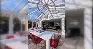 A modern interior with a glass ceiling, a dining area with red chairs, and a living space with a sofa and coffee table.