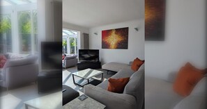 Un salon moderne avec un canapé, une table basse et un téléviseur à écran plat.