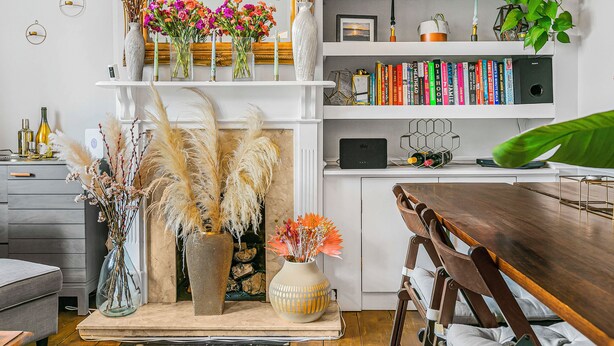A modern living room with a fireplace, bookshelves, and decorative vases. - Charming 2BR Family Home with Private Garden (Greater London)