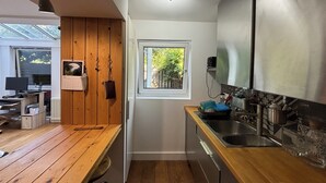 Cocina compacta con suelo de madera, lavaplatos empotrado y ventana que proporciona luz natural.
