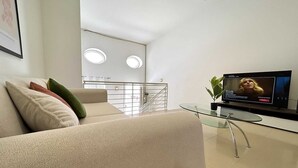 A modern living room with a sofa, a glass coffee table, and a flat-screen TV. - Private BBQ + outdoor + fun area St. Julians (St Julians)