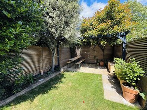 Un jardin avec une clôture en bois, une pelouse verdoyante et une pergola en bois.