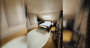 Une chambre avec une lucarne, un lit, un bureau et une chaise.