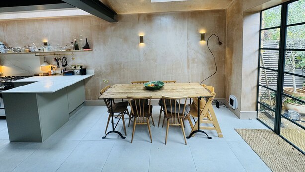 Una cocina moderna con una isla central, sillas de madera y una mesa de comedor.