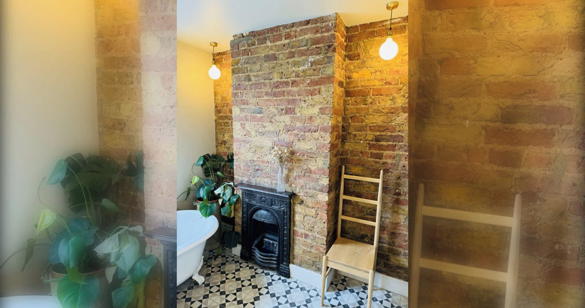 A bathroom with a brick wall, a black bathtub, a wooden chair, and a white toilet.