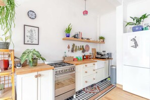 A kitchen with a stove, oven, and various plants. - Modern Farmhouse-Style 1BD Flat - Wood Green! (Greater London)