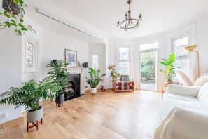 Un salon spacieux doté d’une cheminée, de parquet et de grandes fenêtres.