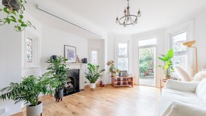 Un amplio salón con chimenea, ventanas grandes y varias plantas en macetas.