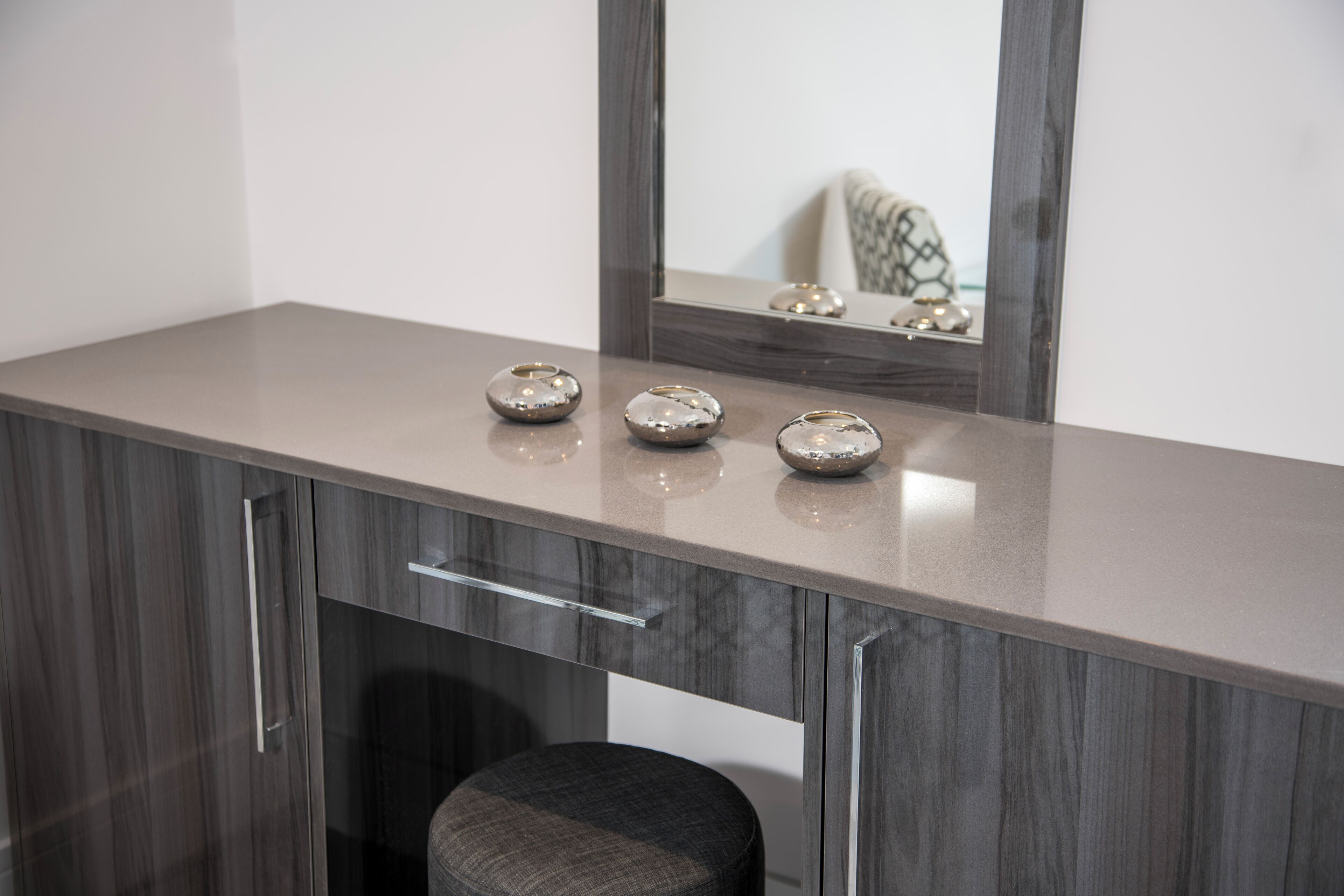 A bathroom vanity with a mirror, a countertop, and a stool.