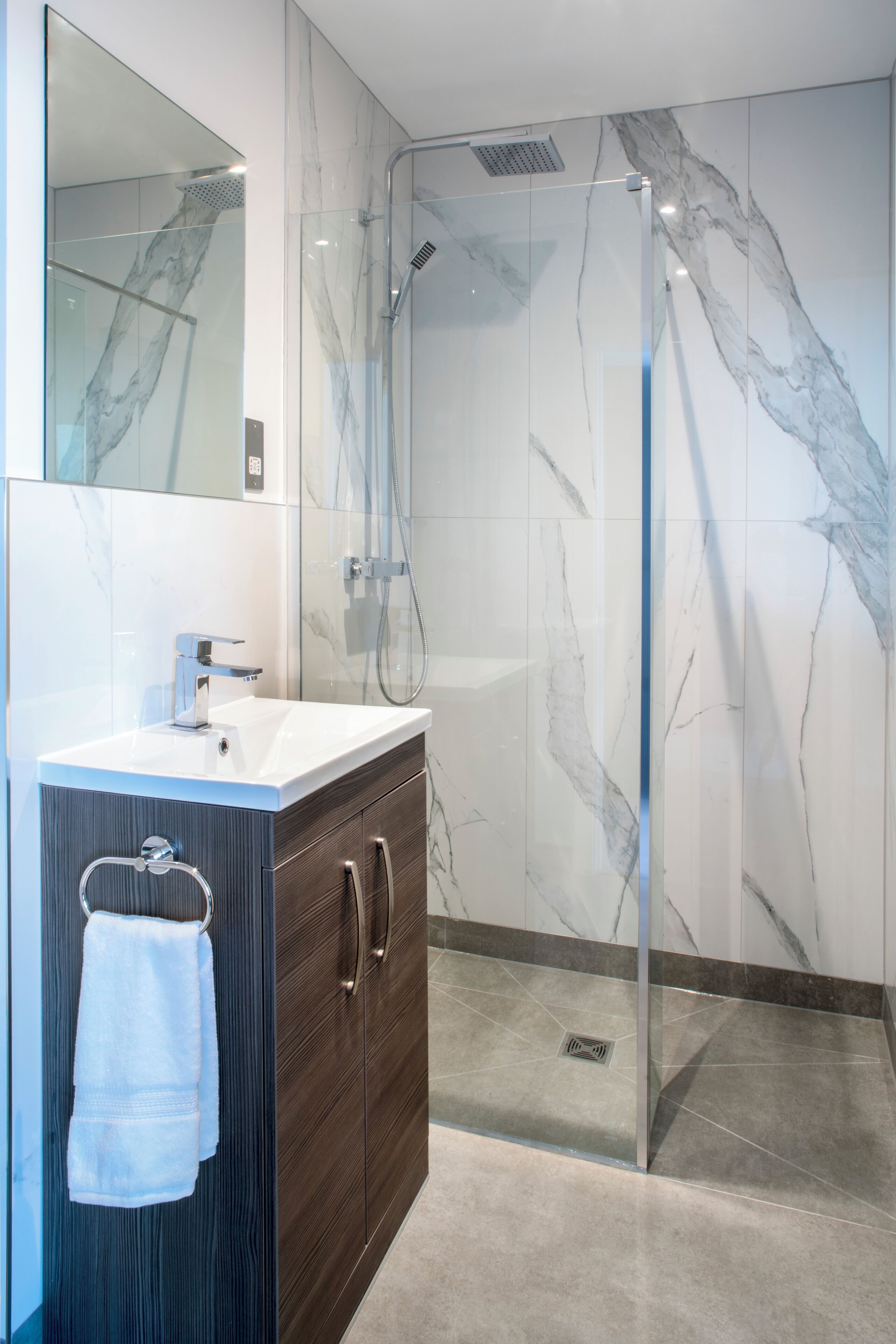 A modern bathroom with a glass-enclosed shower, a white sink, and dark wooden cabinets.