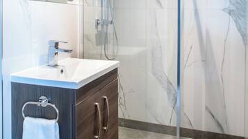 A modern bathroom with a glass-enclosed shower, a white sink, and dark wooden cabinets.