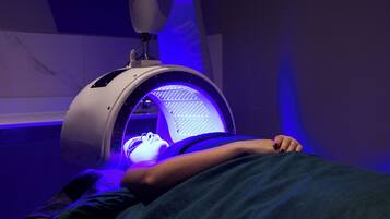 Experience soothing health treatments in a clinical setting with a therapeutic light therapy machine positioned above a comfortable reclining chair.