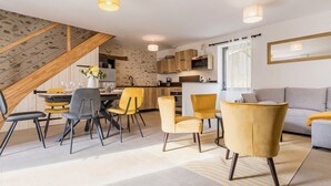 A modern living room with a dining area, a kitchen, and a staircase.