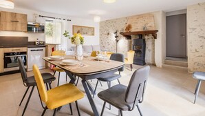 A modern kitchen with wooden cabinets, a built-in oven, and a dining area with a table set for four.