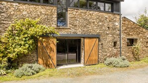 A modern house with a stone facade, large windows, and a wooden door.