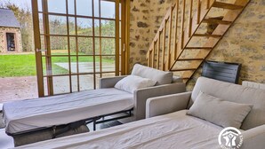 Ein Zimmer mit einem Bett, zwei Sofas, einer Holztreppe und einem großen Fenster.