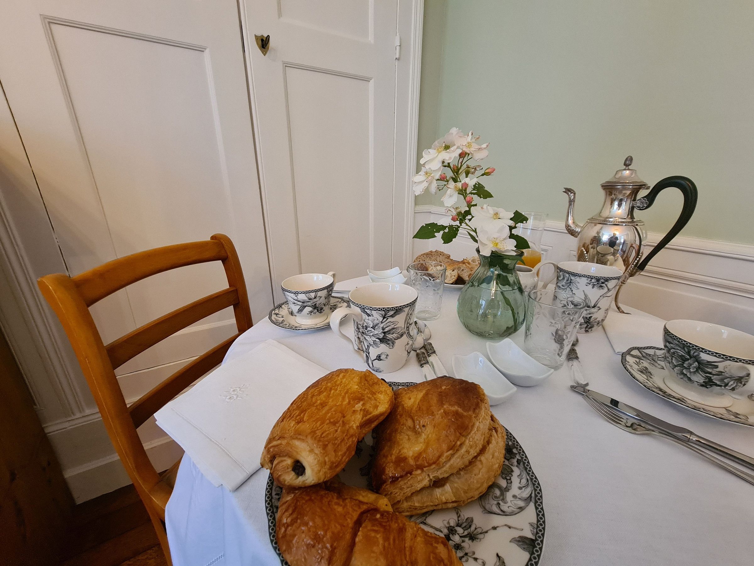 Ein Frühstückstisch mit Gebäck, einer Karaffe und Teetassen.